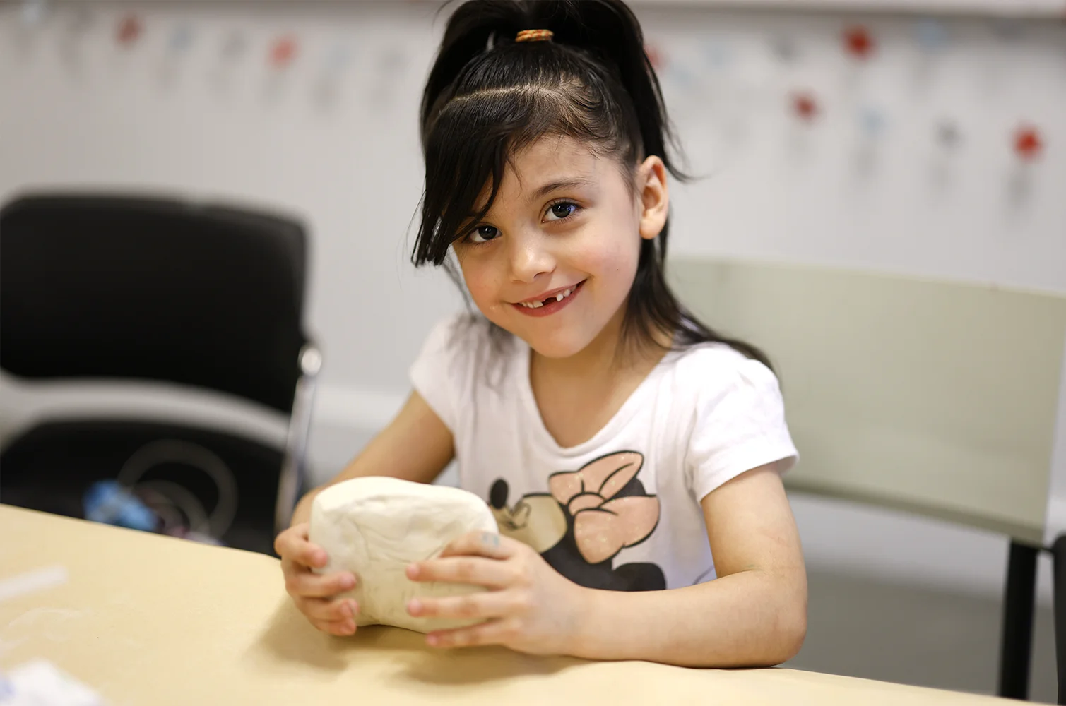 A child smiling and holding clay