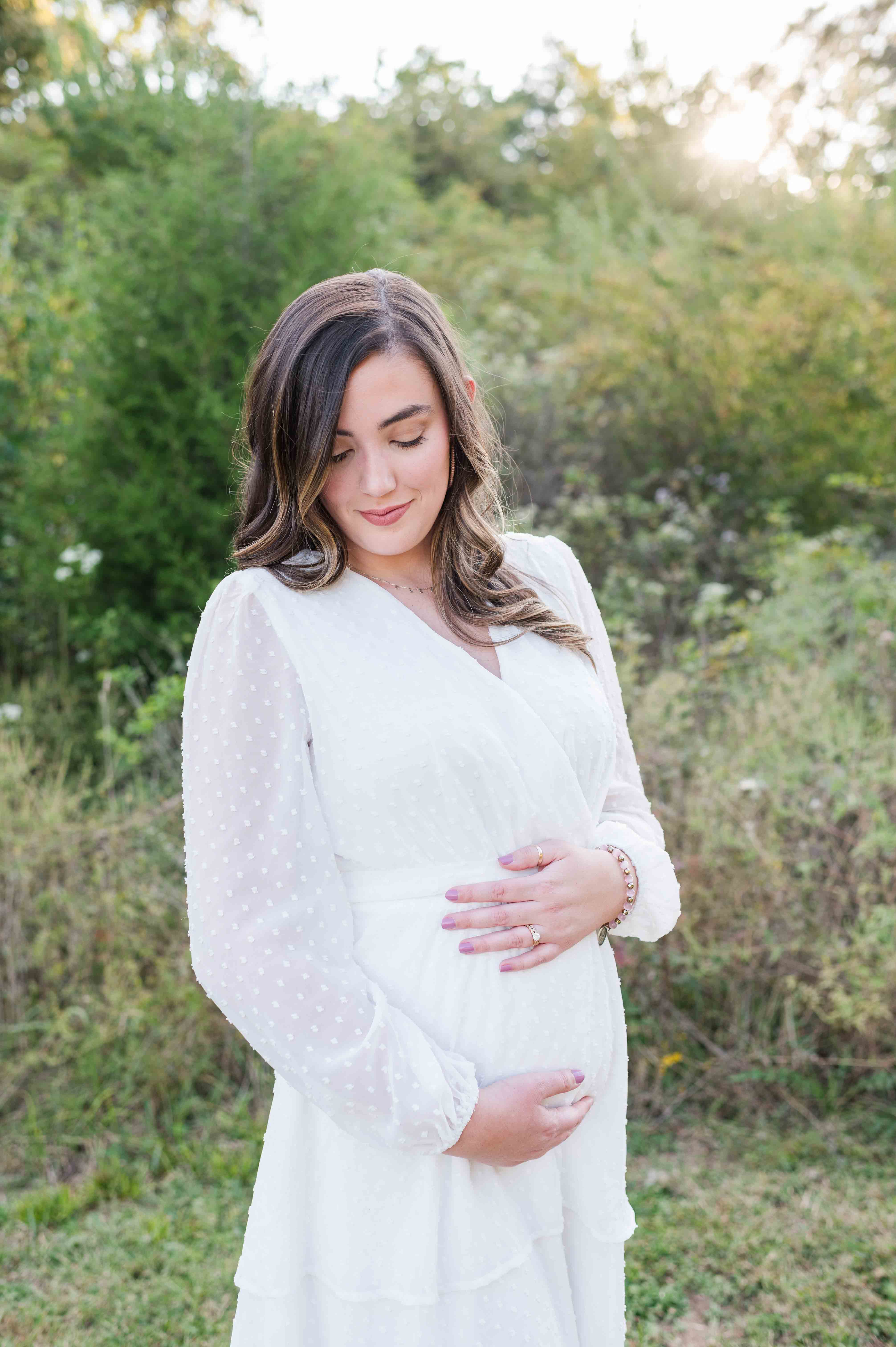 Maternity session in park with mom holding her belly.