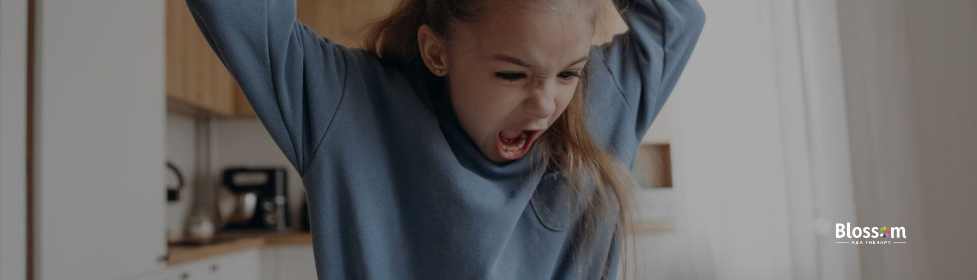 A girl with autism angrily throwing a pen in frustration while sitting at a table with schoolwork.