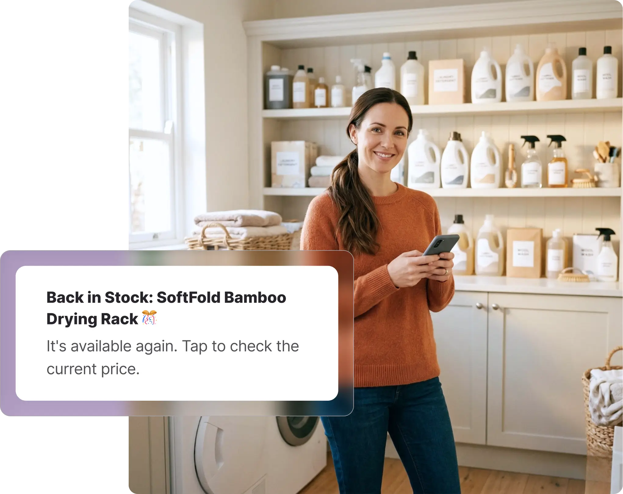 A smiling woman standing in a brightly lit laundry room holding her smartphone, next to a washing machine and shelves stocked with household cleaning products. Overlaid on the image is a Whisprice digital notification displaying a back-in-stock alert for a Target product, specifically the "SoftFold Bamboo Drying Rack," prompting the user to tap and check the current price.