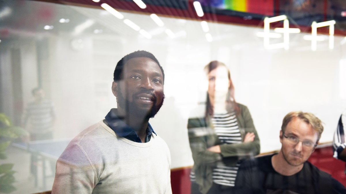 Three workshops participants looking at a glass wall filled with notes during a workshop