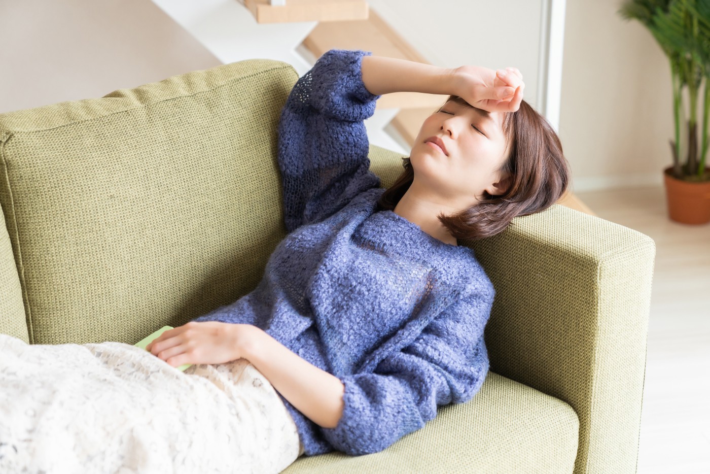 疲れてソファーで横になる女性