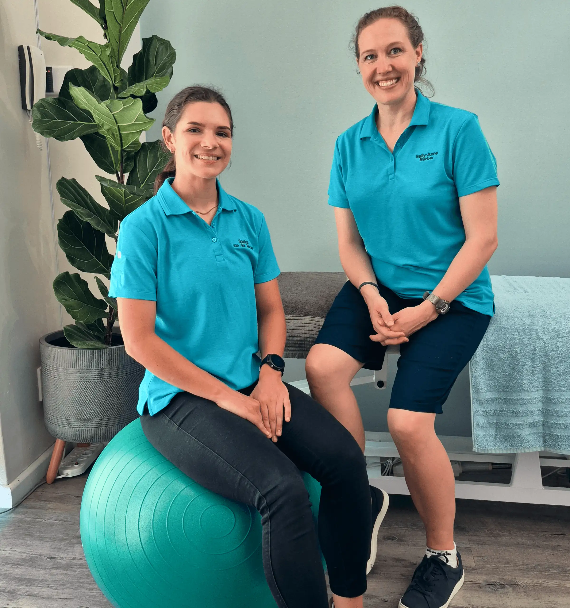 Two Physical therapist women smiling and sitting in a clinic.