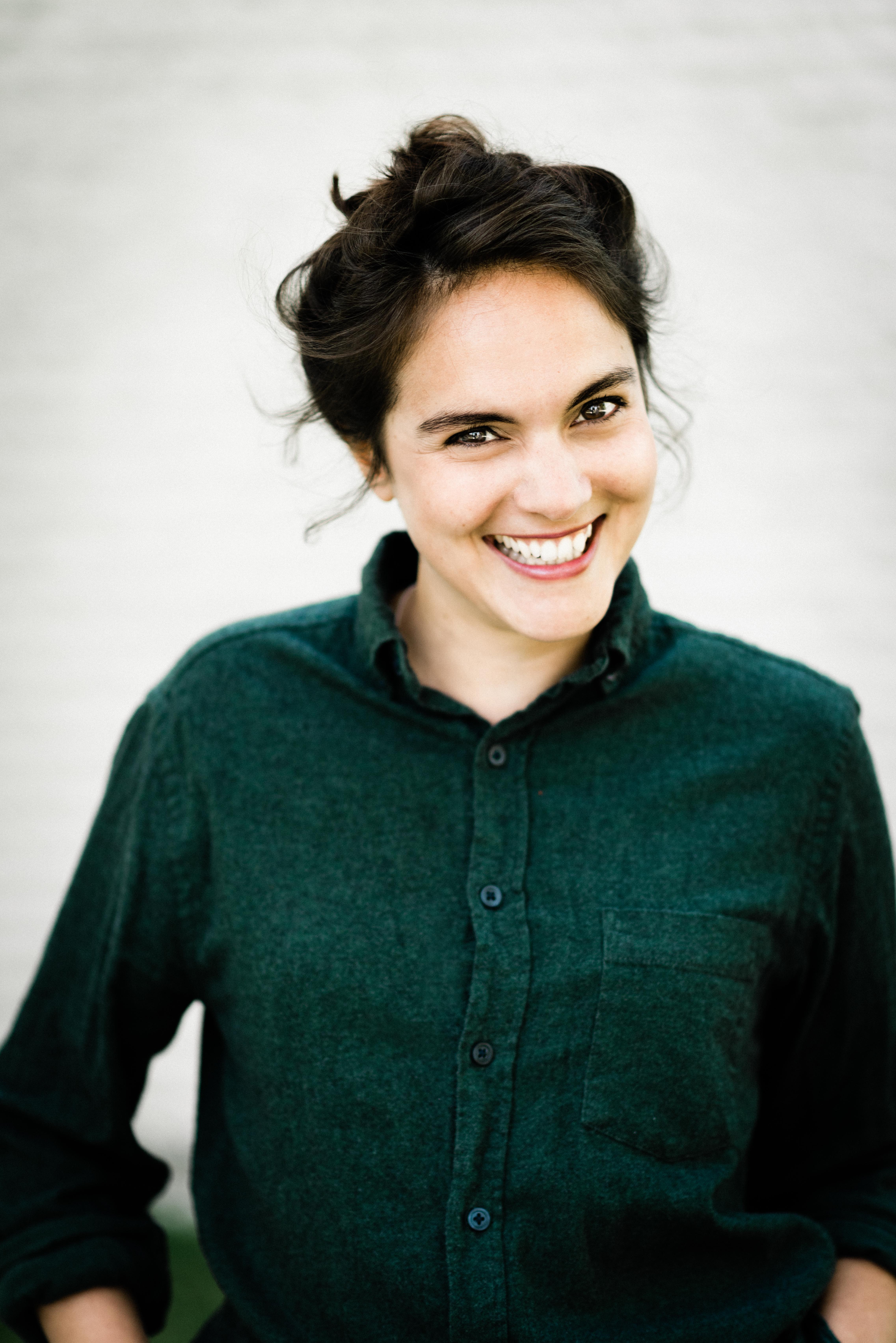 headshot casting photo of Joanna Lucas, actor, smiling woman with dark updo, green shirt, bright exterior.