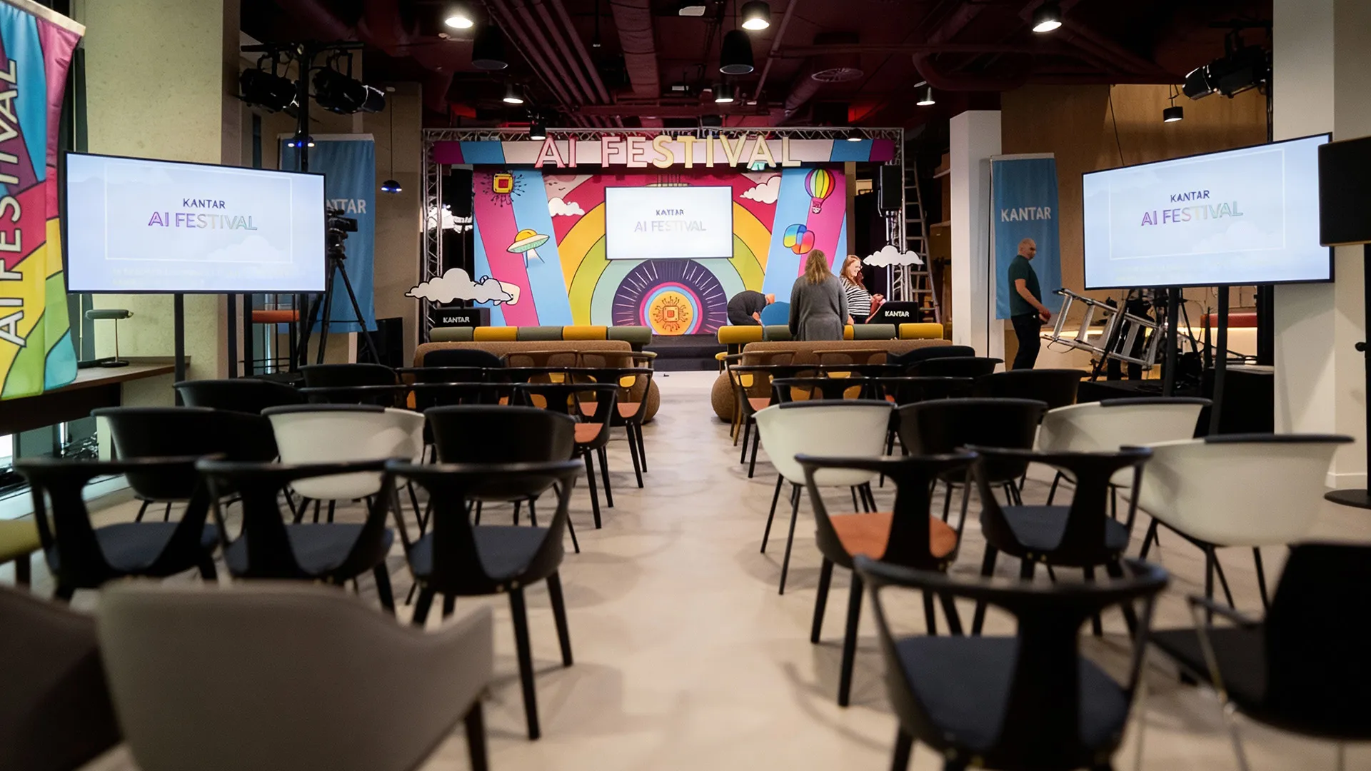 Wide view of the Kantar AI Festival stage setup, with branded backdrop, screens and seating inside the event space.