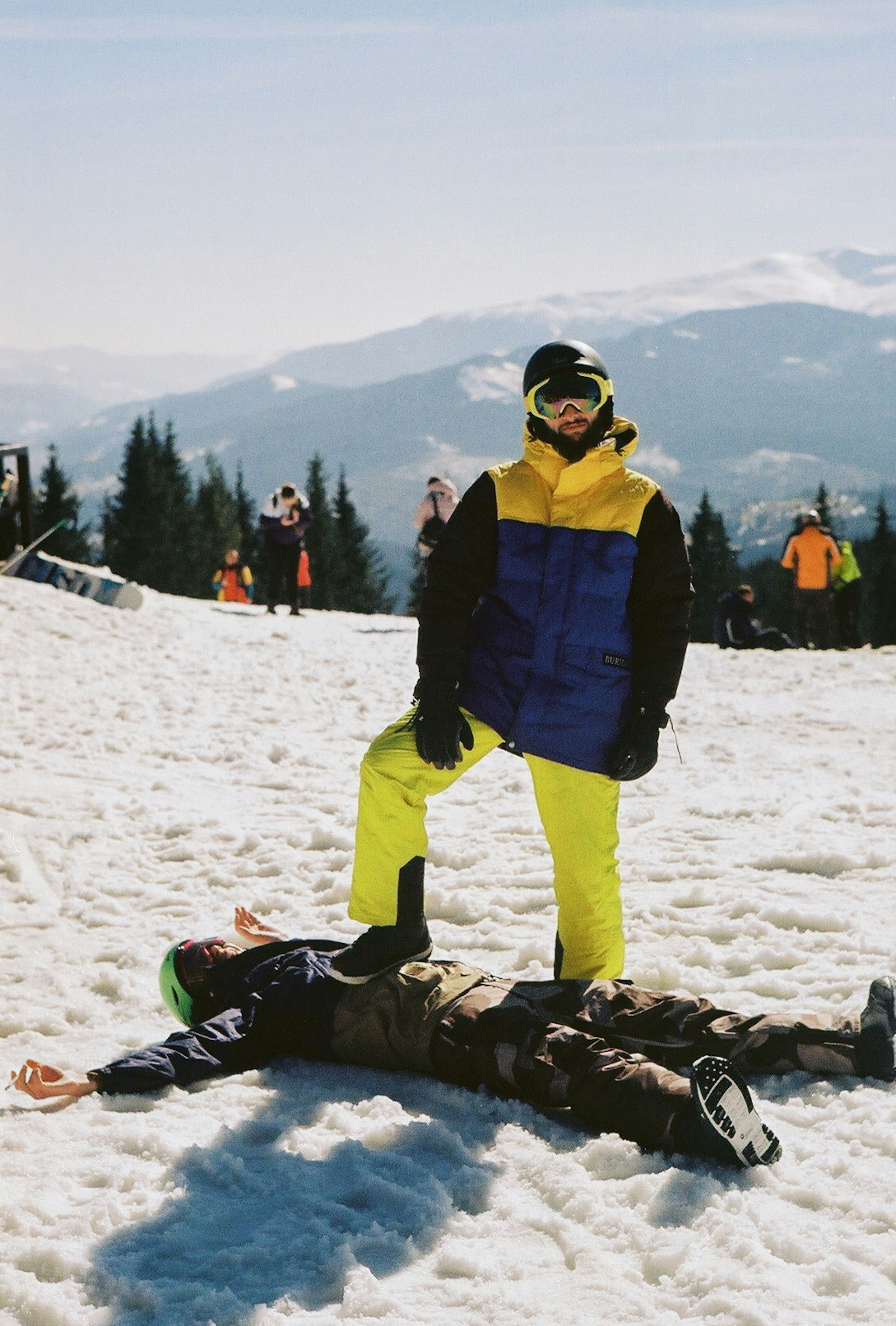 Man standing on another man in the snow.
