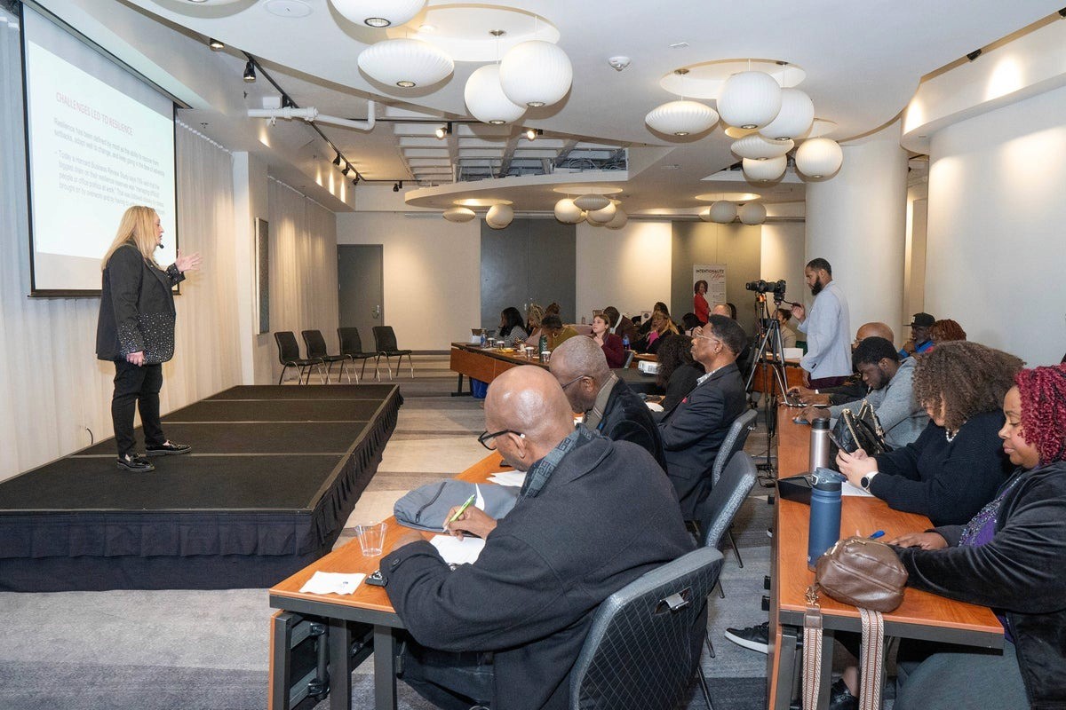 Alicia Pozsony speaks on stage to attendees during a resilience and leadership development workshop.
