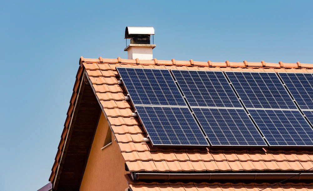 Solar panels installed on the roof of a building, with a clear blue sky in the background.