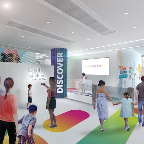 People, including children and adults, walk through an interactive exhibit area with colorful paths, a "Discover" pillar, and "Opening soon" sign.