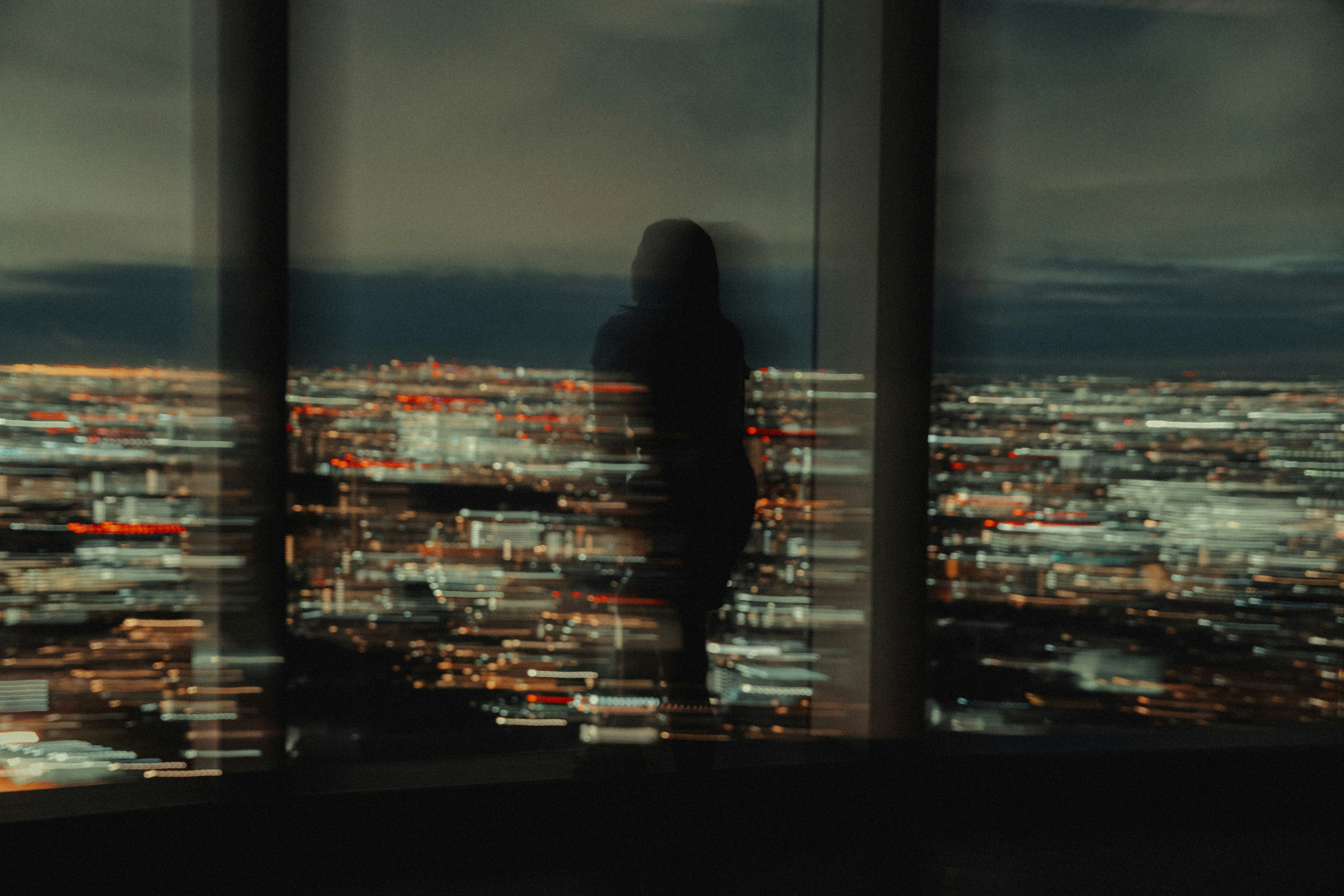 A person sits at a cluttered desk with blurred motion, surrounded by books and art, in a softly lit, creative workspace.