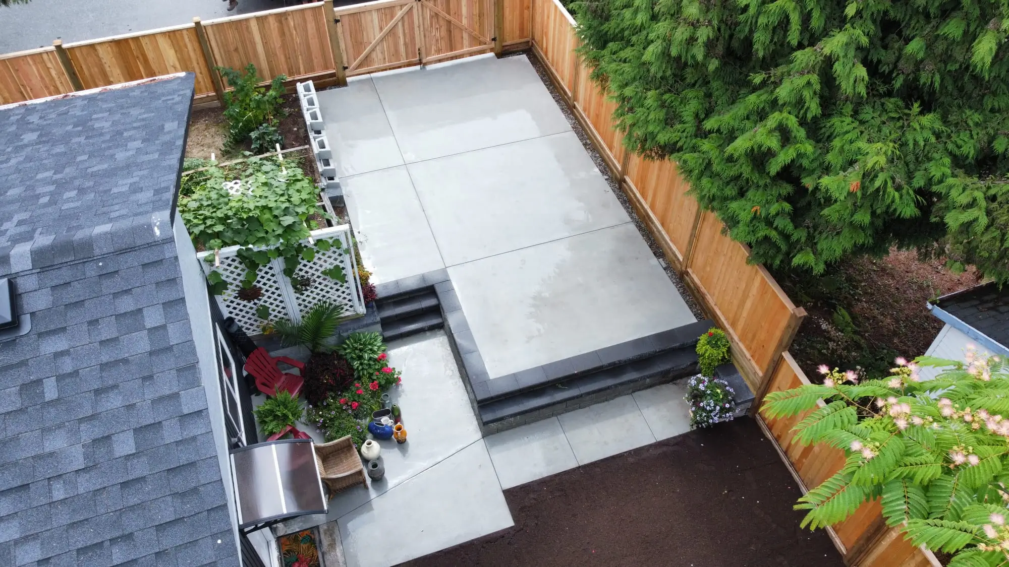 Backyard concrete patio with tiered steps and wood privacy fencing.