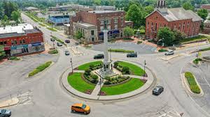 Aerial view of an intersecting dirt pathway forming an X-shape surrounded by lush greenery and arid, rocky terrain, illustrating a contrasting landscape.