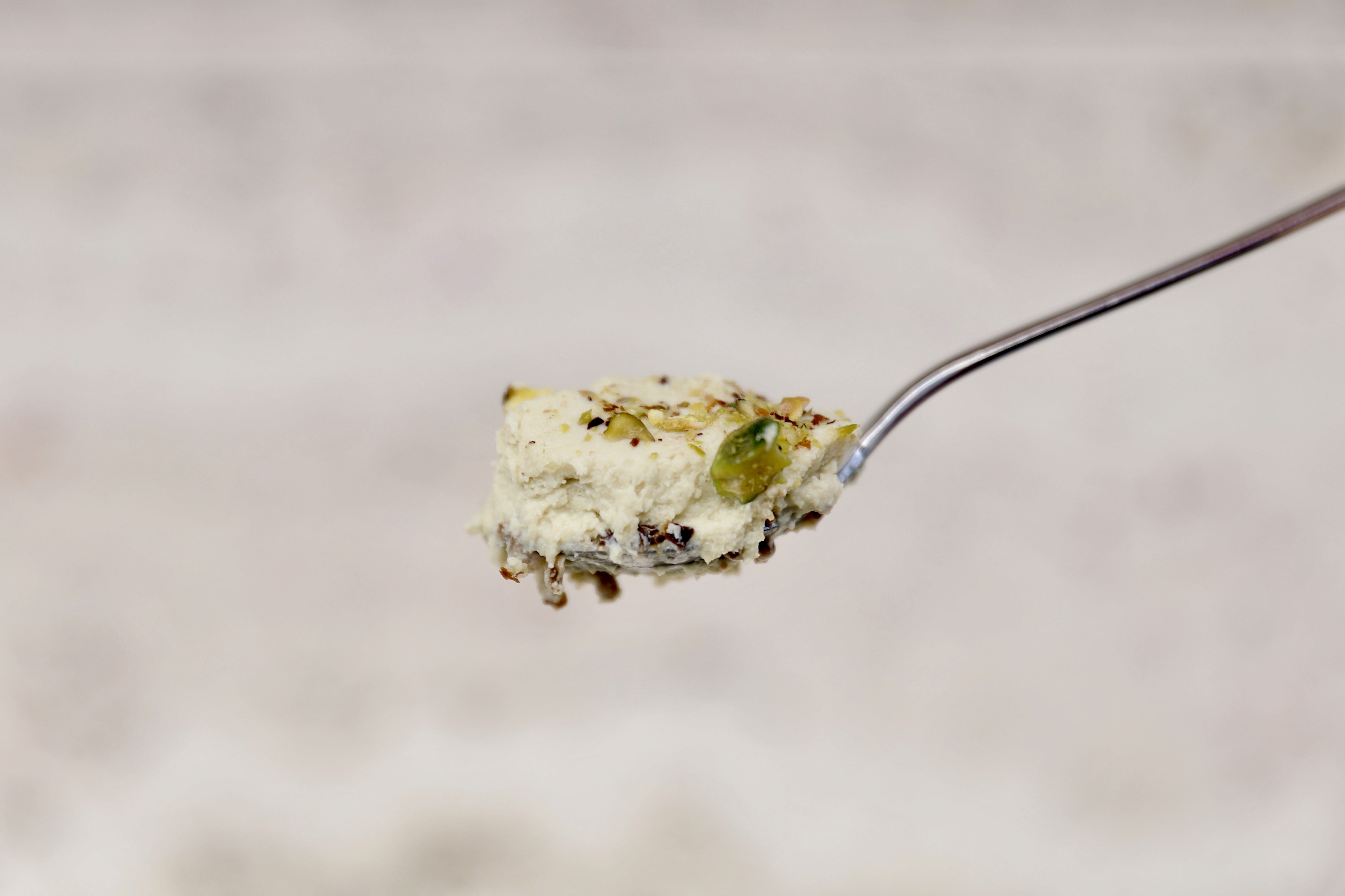 Creamy pistachio dessert on a spoon with crushed nuts and delicate texture