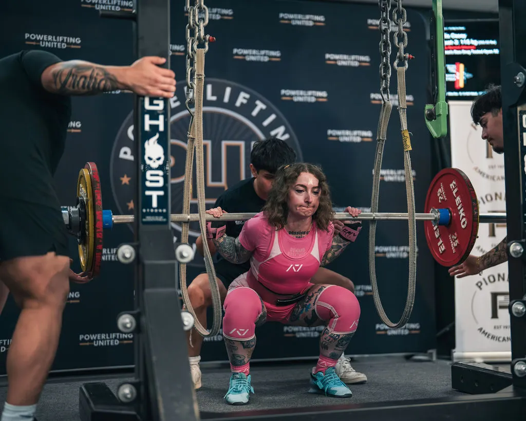 Female powerlifter squatting with Pioneer calibrated plates at a Powerlifting United meet
