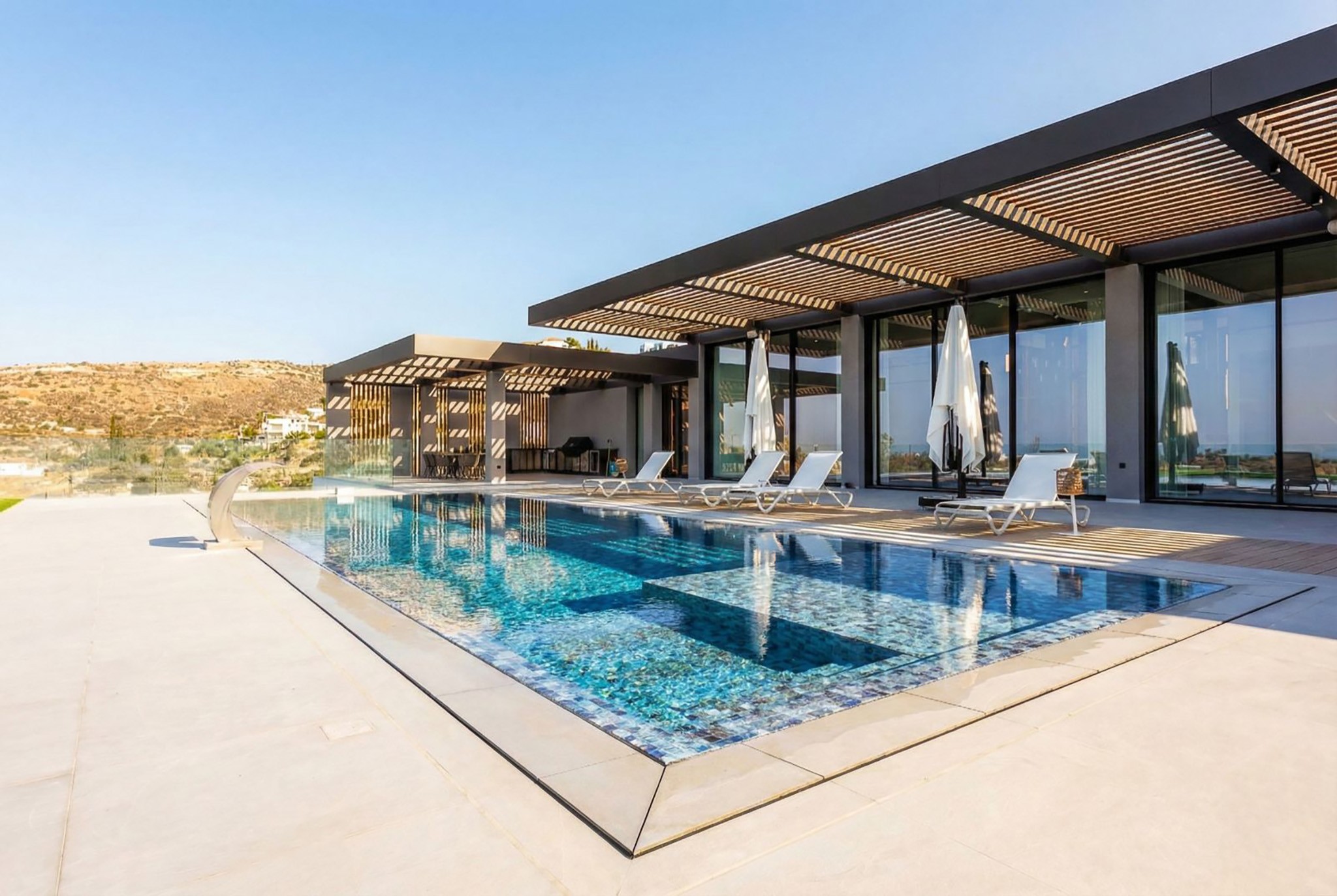 Villa Trio pool terrace with pergola shading, sun loungers, and full-height glazing, by Roomzly