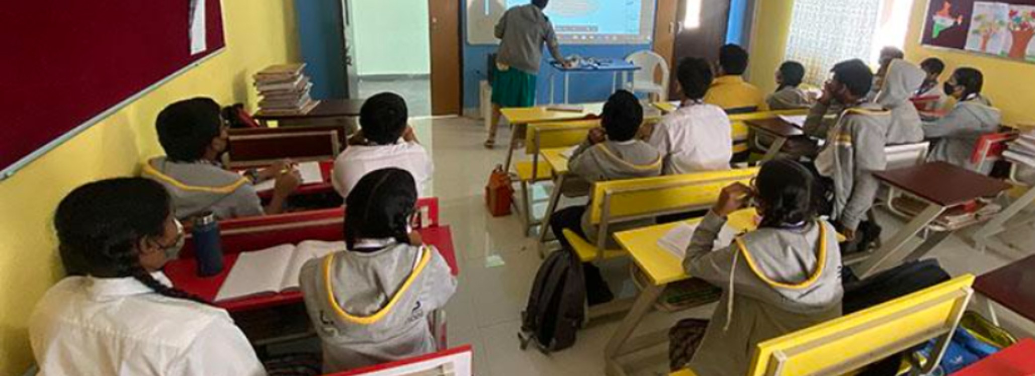 Students in a modern classroom with teacher presenting