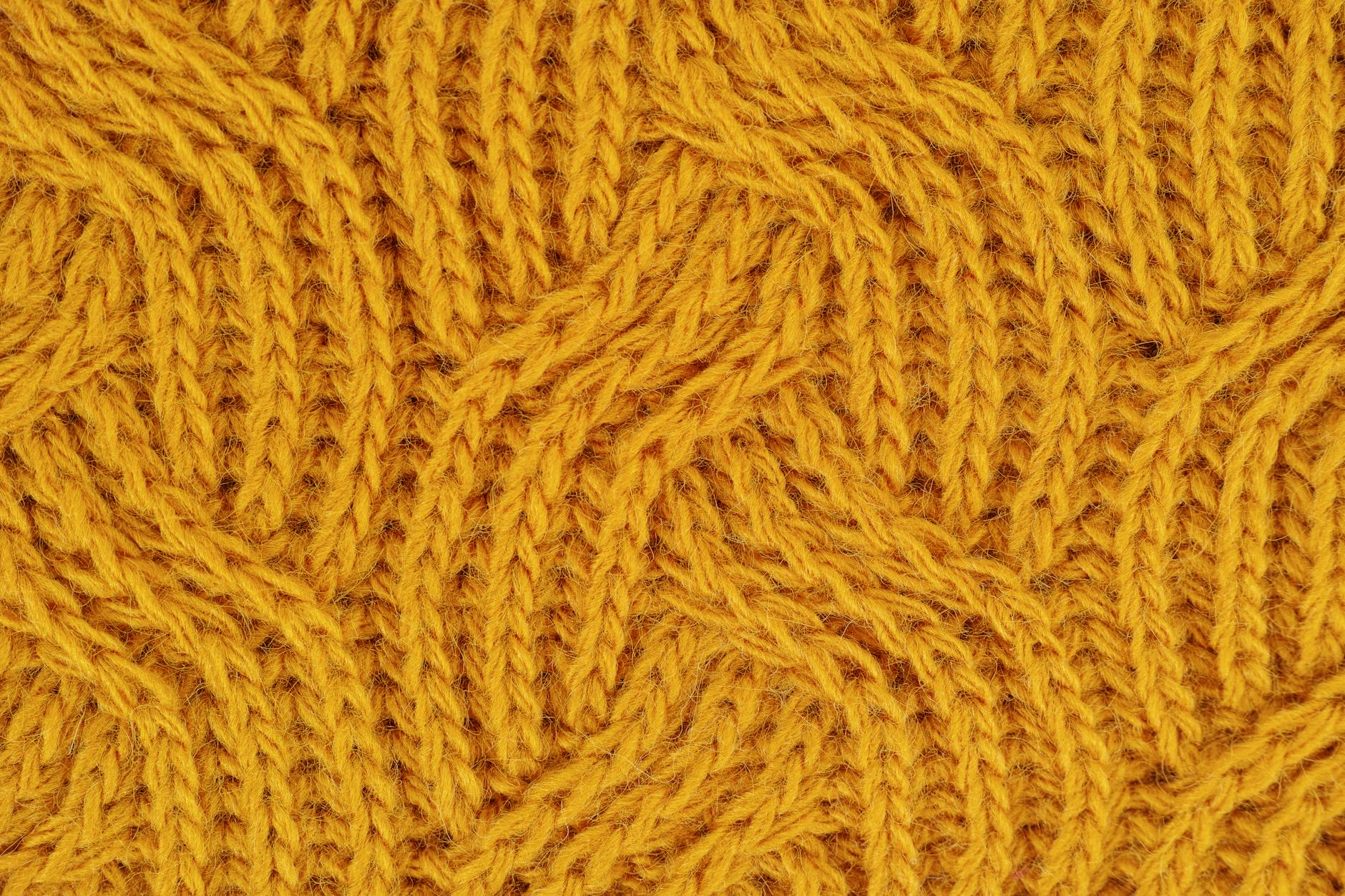 Detailed close-up of a yellow knitted wool pattern, ideal for textile design.