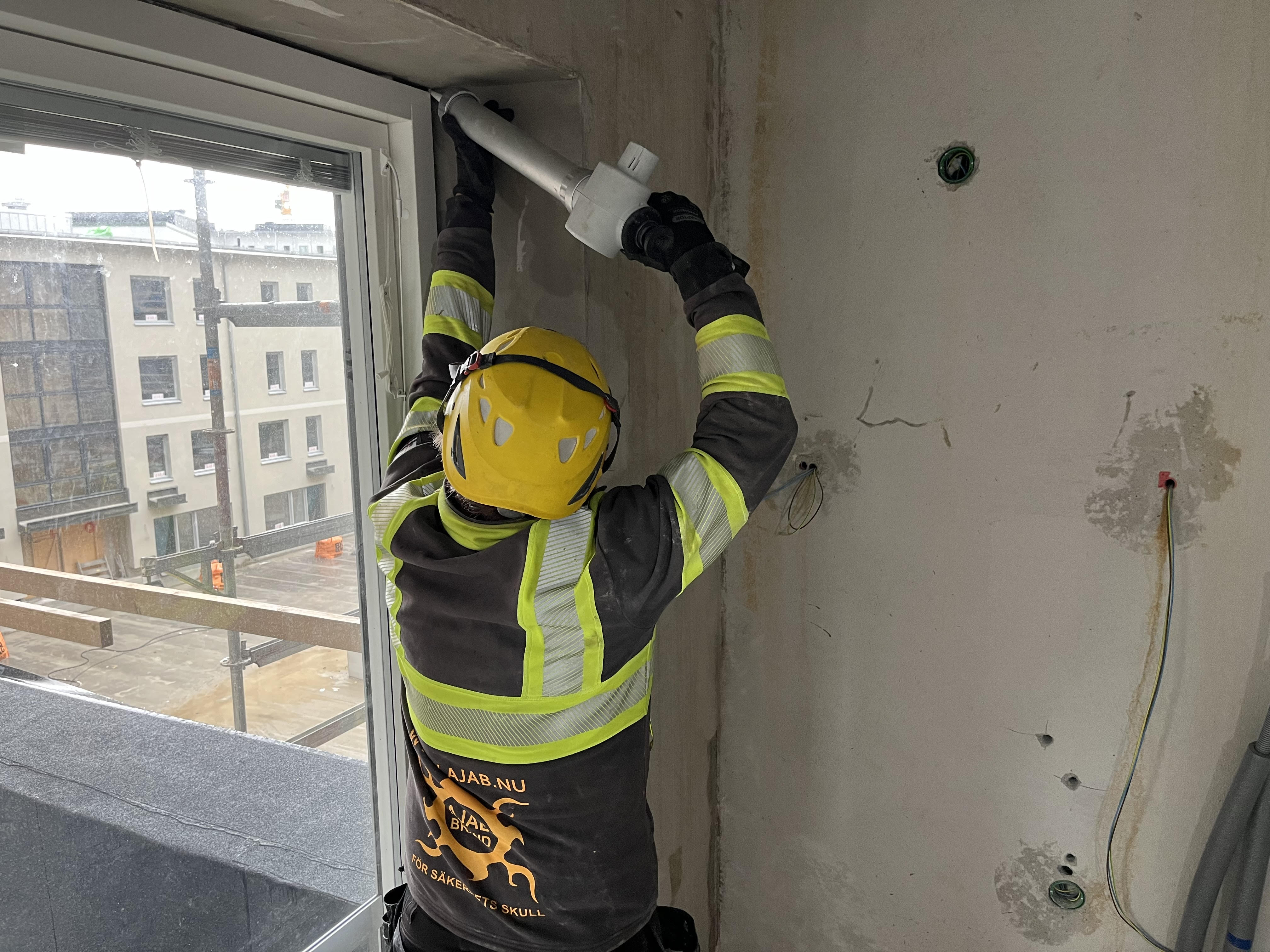 Montör från AJAB Brand utför brandskyddsisolering vid fönstersmyg i byggnad
