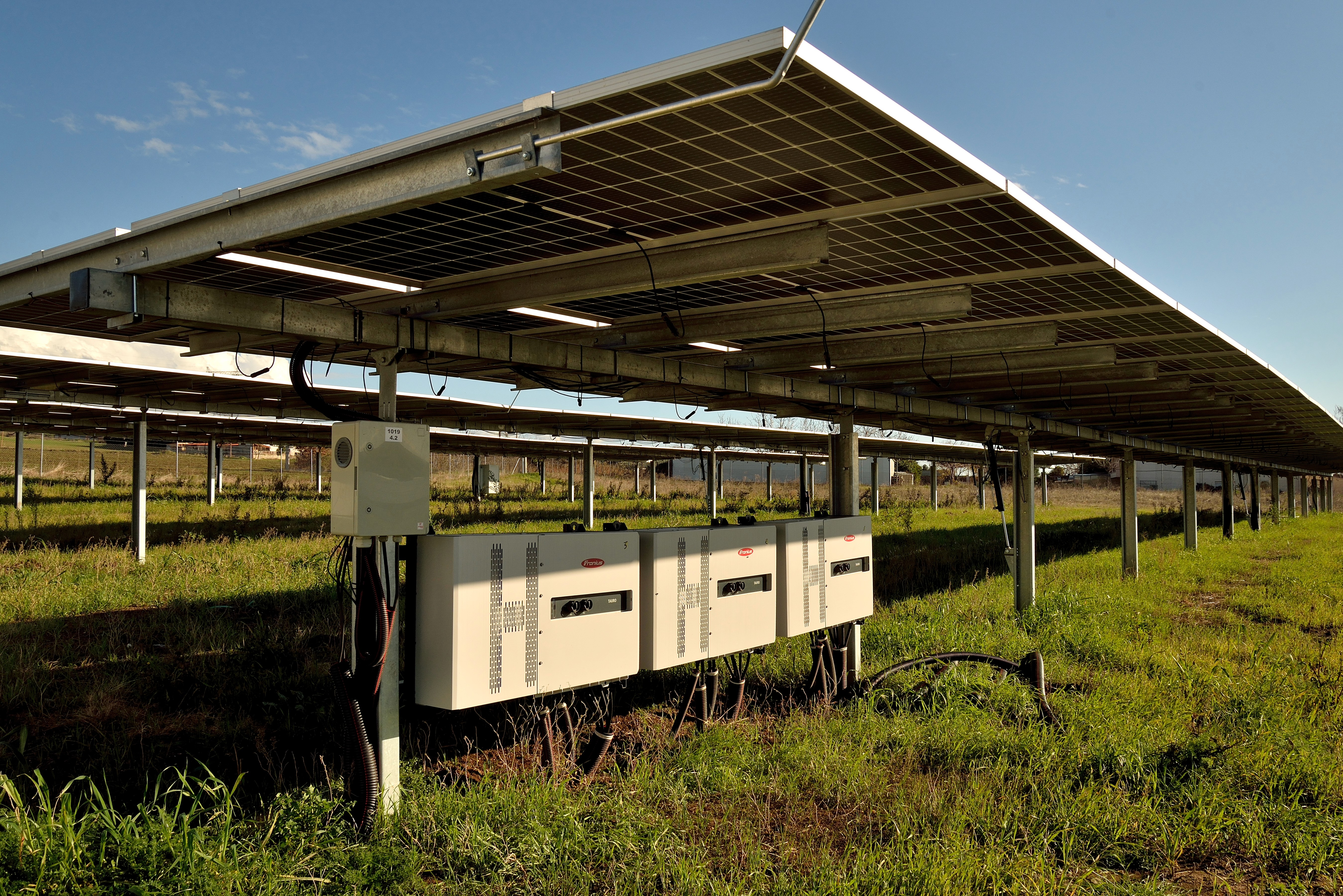 String inverters installed beneath ground-mounted photovoltaic panels within solar power plant