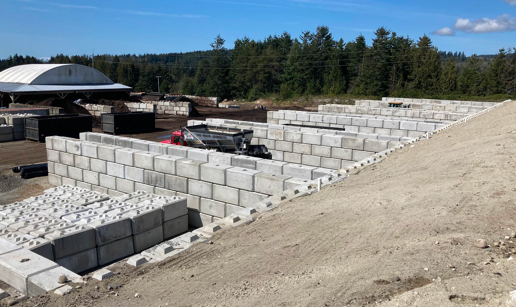 Lock block retaining wall construction creating material storage bays at Salish Soils commercial property