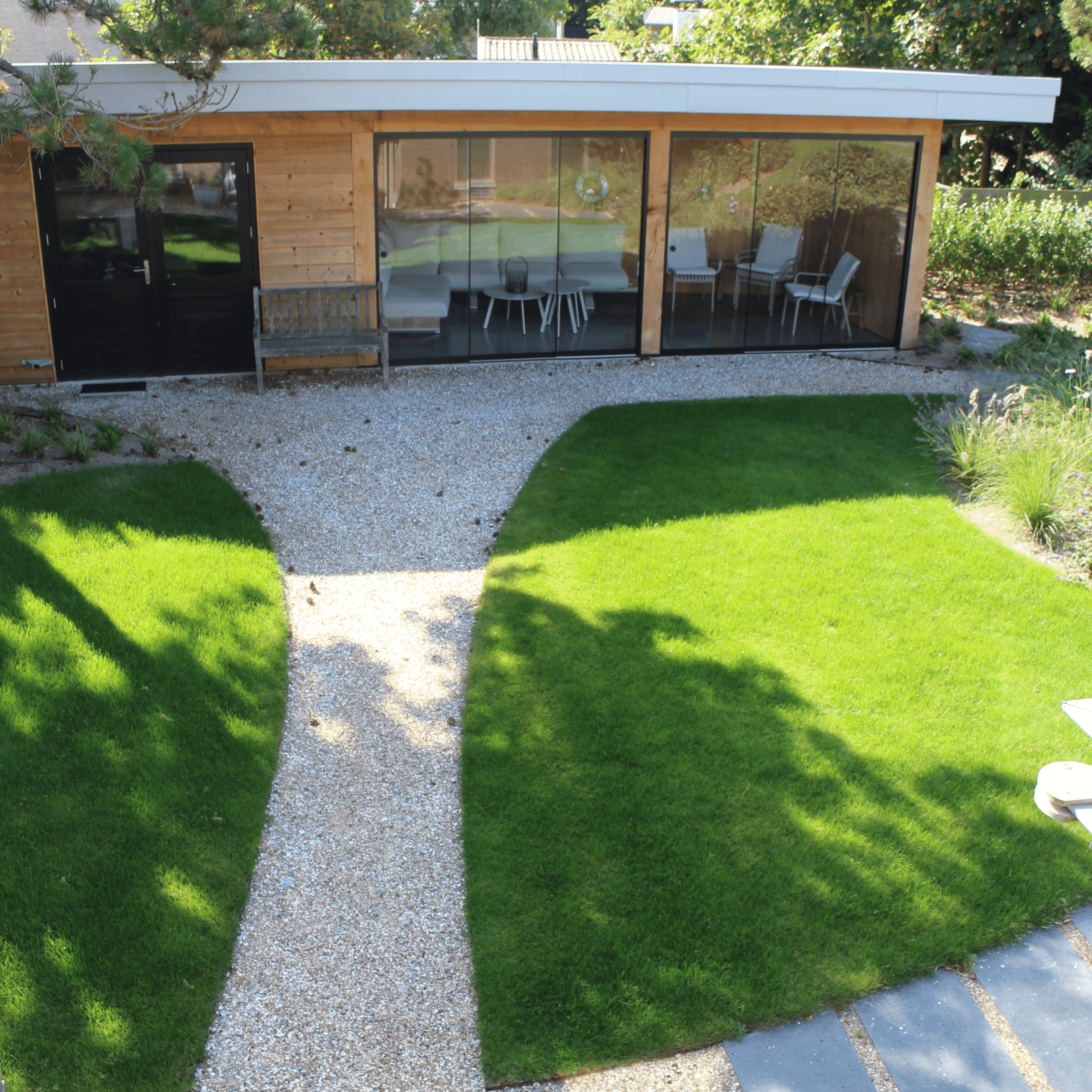 Modern open-concept living room with a large beige sectional, a wall-mounted TV, sleek barstools, wooden accents, and natural light from large windows. Cozy atmosphere.