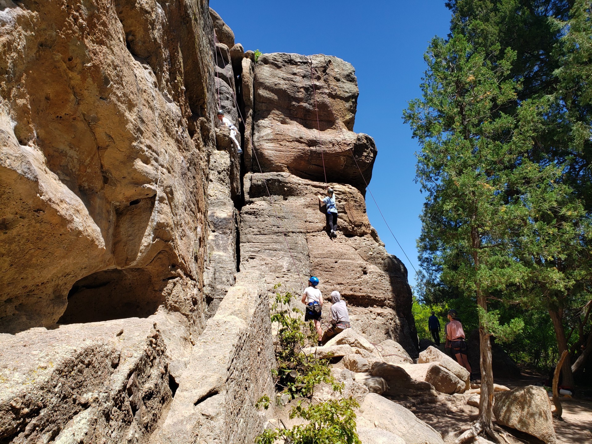 Belayer and backup belayer look up at climber in middle of climb at Castlewood Canyon