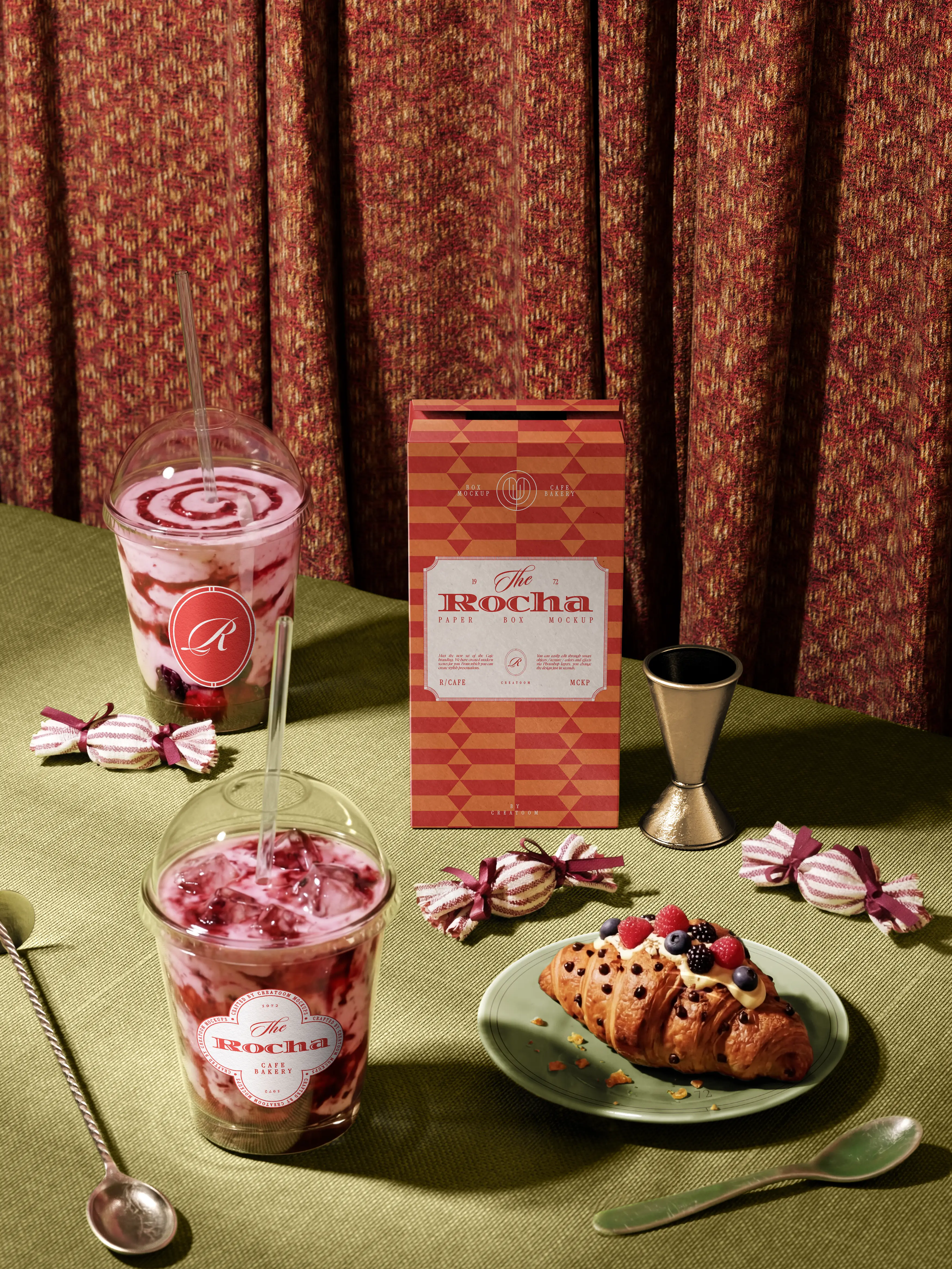 Iced desserts, pastries and a red patterned bakery box on a green table