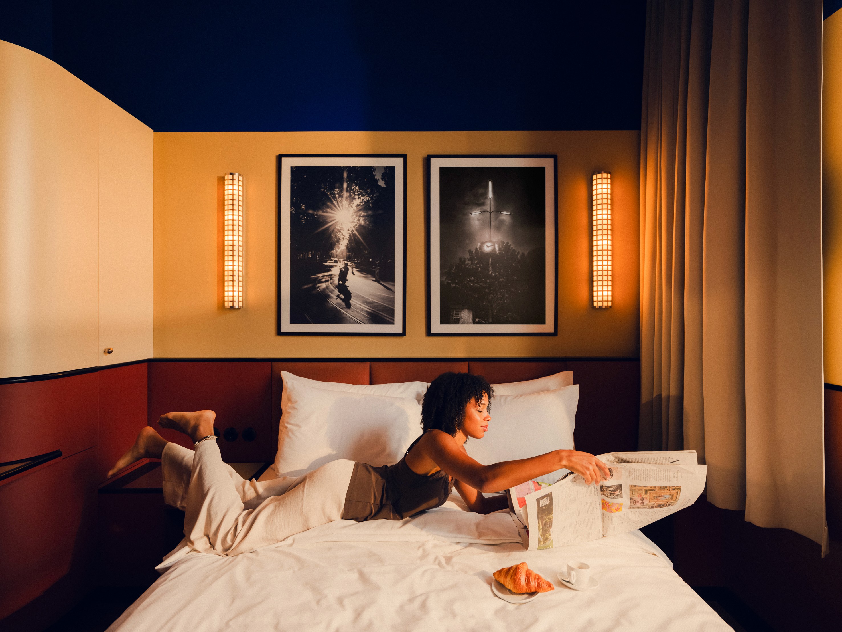 Woman laying in bed, reading a newspaper in the Poet M room at The Companion Vienna