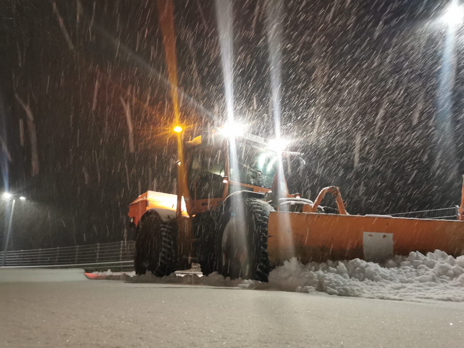 Räumfahrzeug mit Schneeschild im nächtlichen Schneetreiben
