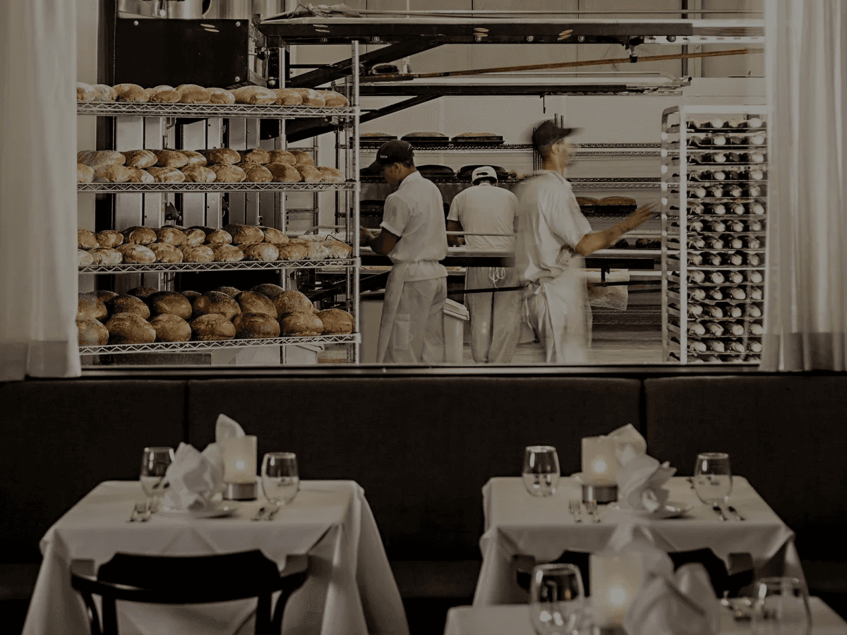 Restaurant dining room interior showing the bakery window with bakers freshly baking bread in the ovens