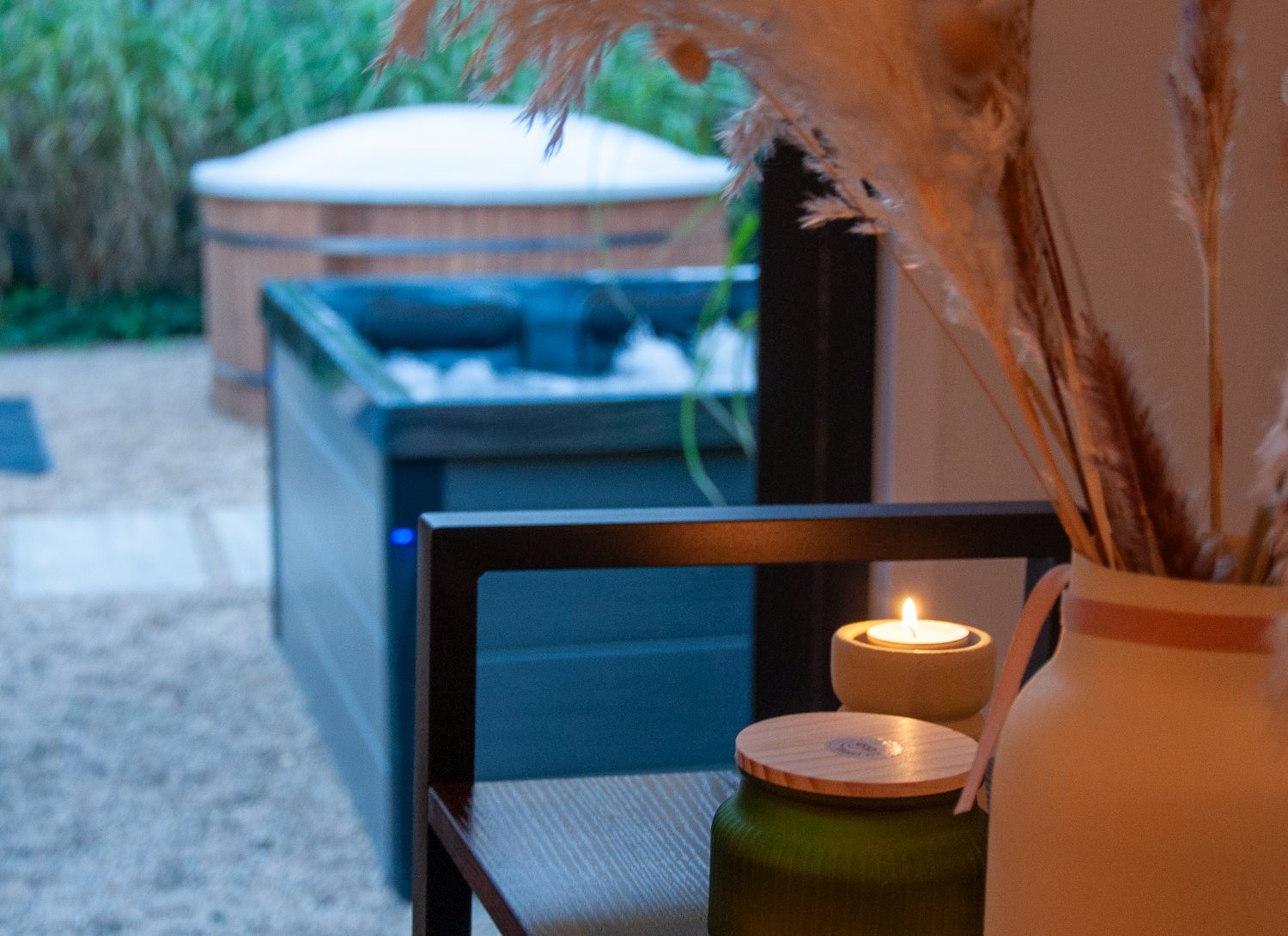 Klimatyczna strefa chillout w Niedźwiedzia 25 – zapalona świeca, dekoracje i widok na prywatne jacuzzi w ogrodzie