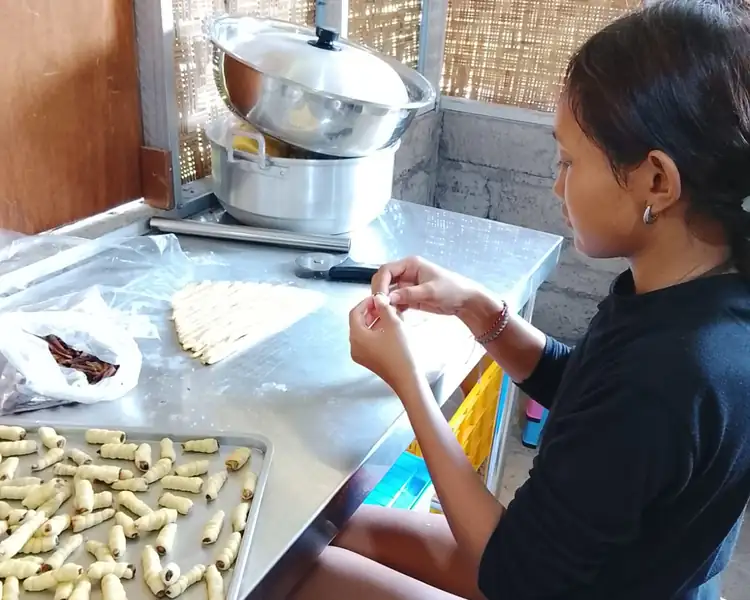 Young woman from our program rolls traditional Indonesian pastries in our women's training kitchen.