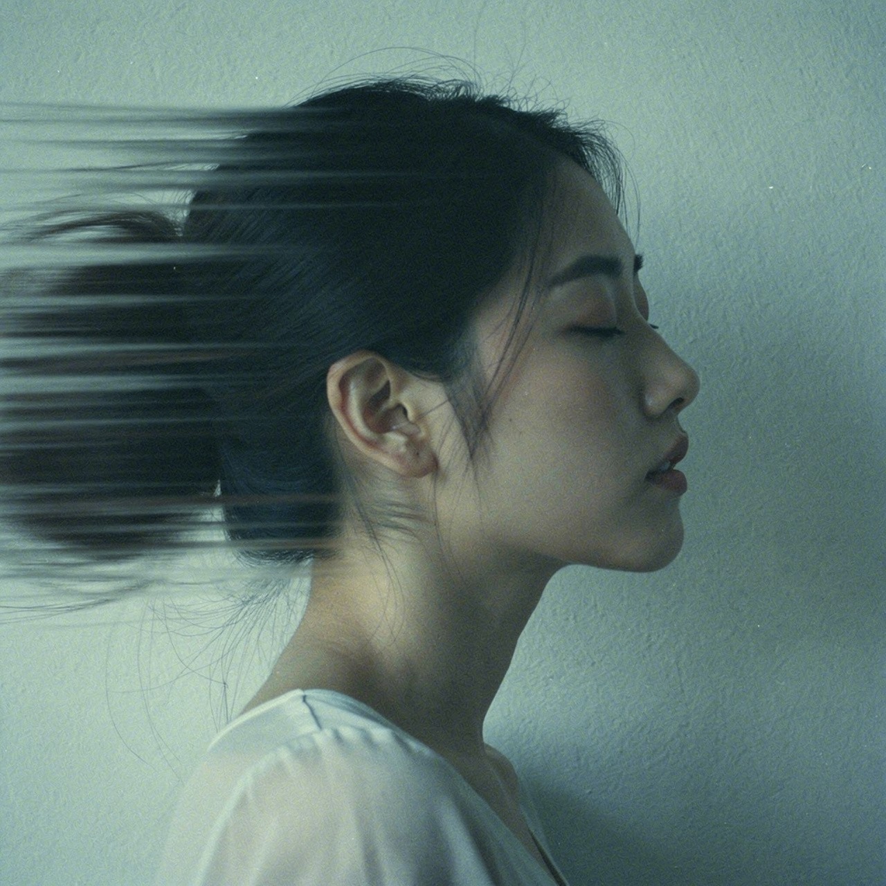 Profile of a woman with closed eyes, blending into motion blur on the left. The serene expression contrasts with dynamic streaks, suggesting introspection.