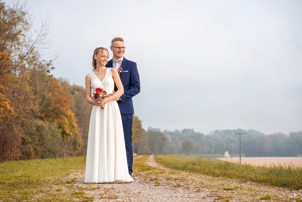 Brautpaar lacht und tanzt auf Feldweg während Hochzeitsshooting