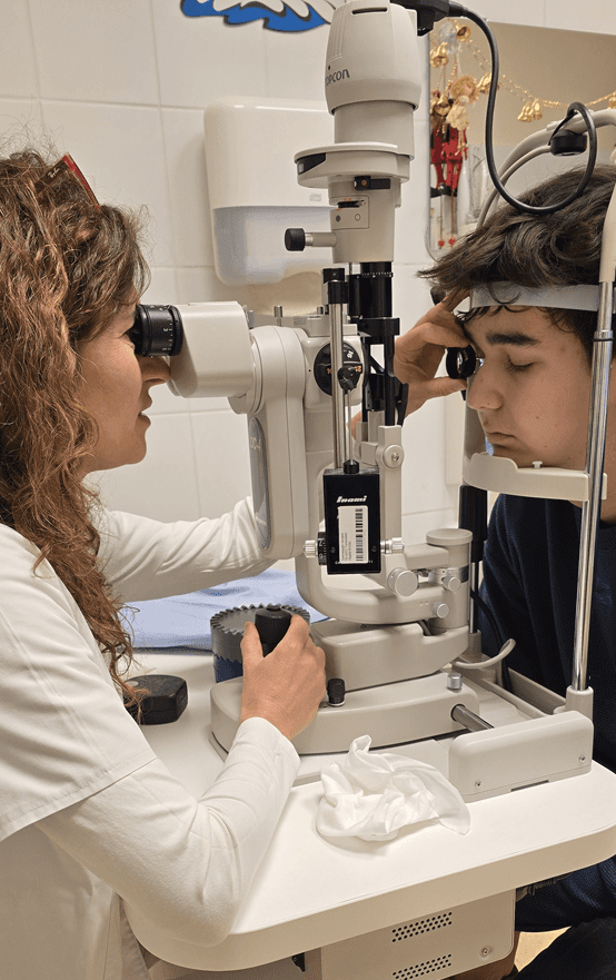 Szemész orvos vizsgál kisgyermeket réslámpával egy szemészeti rendelőben.