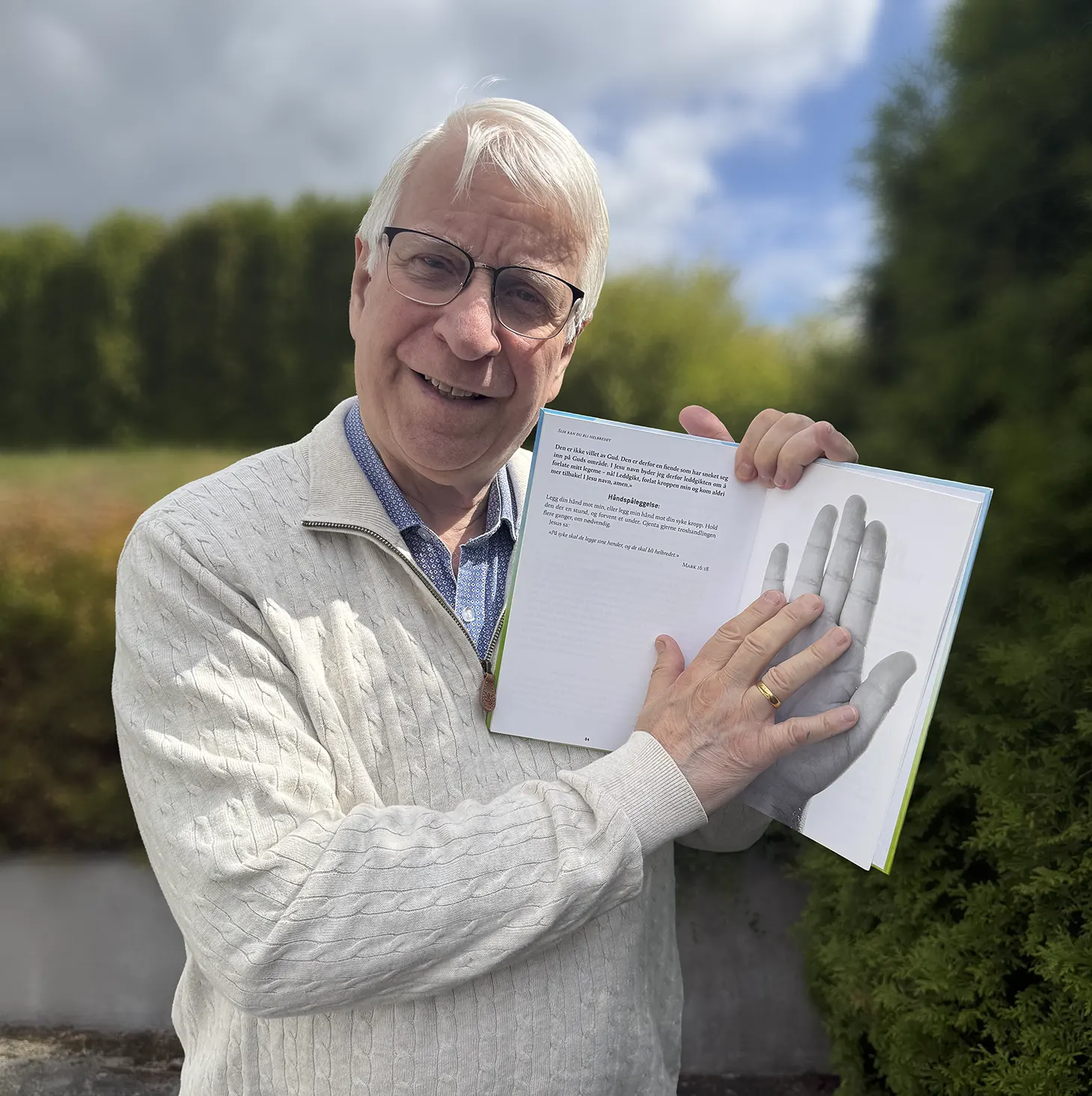 Svein-Magne viser en bok med bilde av sin egen hånd