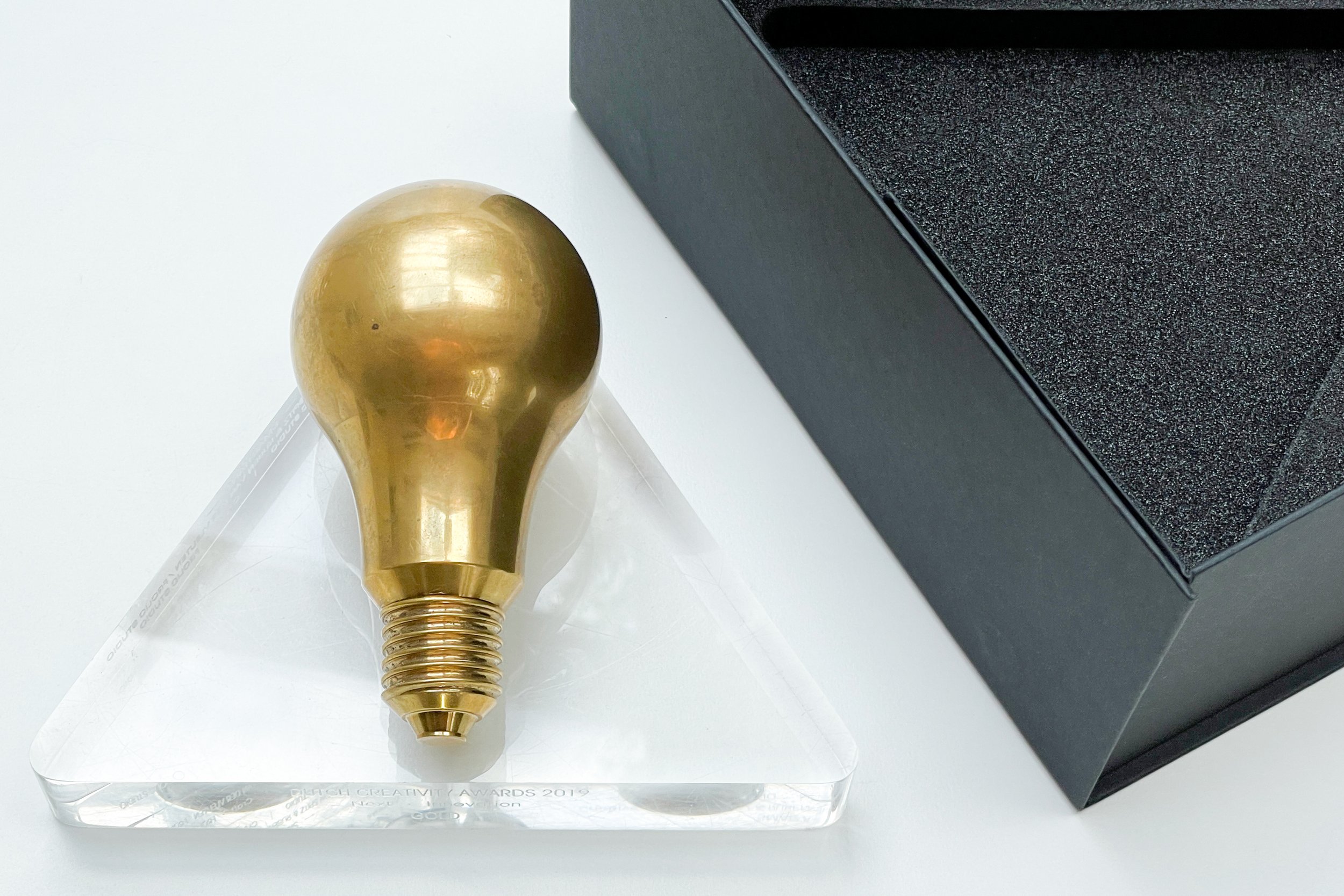 Image of a brass lamp award on a acrylic award base and a black box with foam inlay