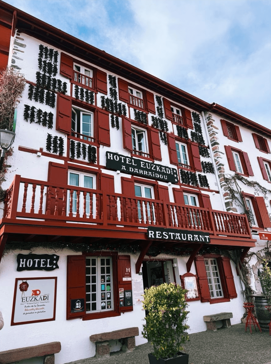 Scenic view of the rugged Basque cliffs and local surfers riding waves at Parlementia break in Guéthary during a guided coastal tour.
