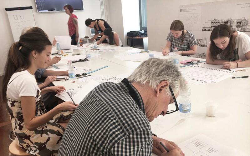 A photo of a group of students working at a table, trying to draw letters for the typography course.