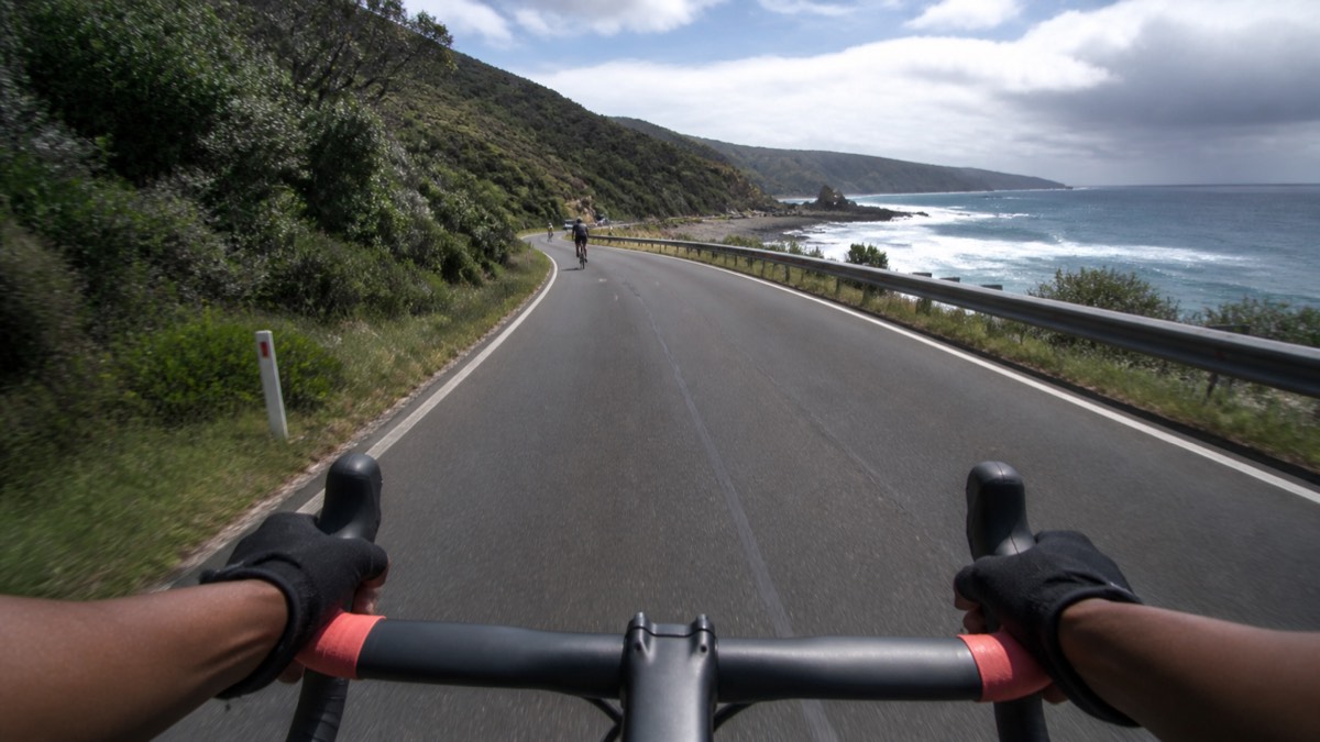 A coastal road and ocean seen over a modern road bicycle cockpit