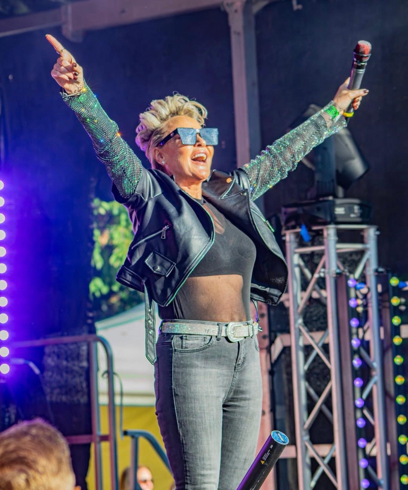Young woman with curly hair in a white outfit sitting on a couch in dim indoor light.