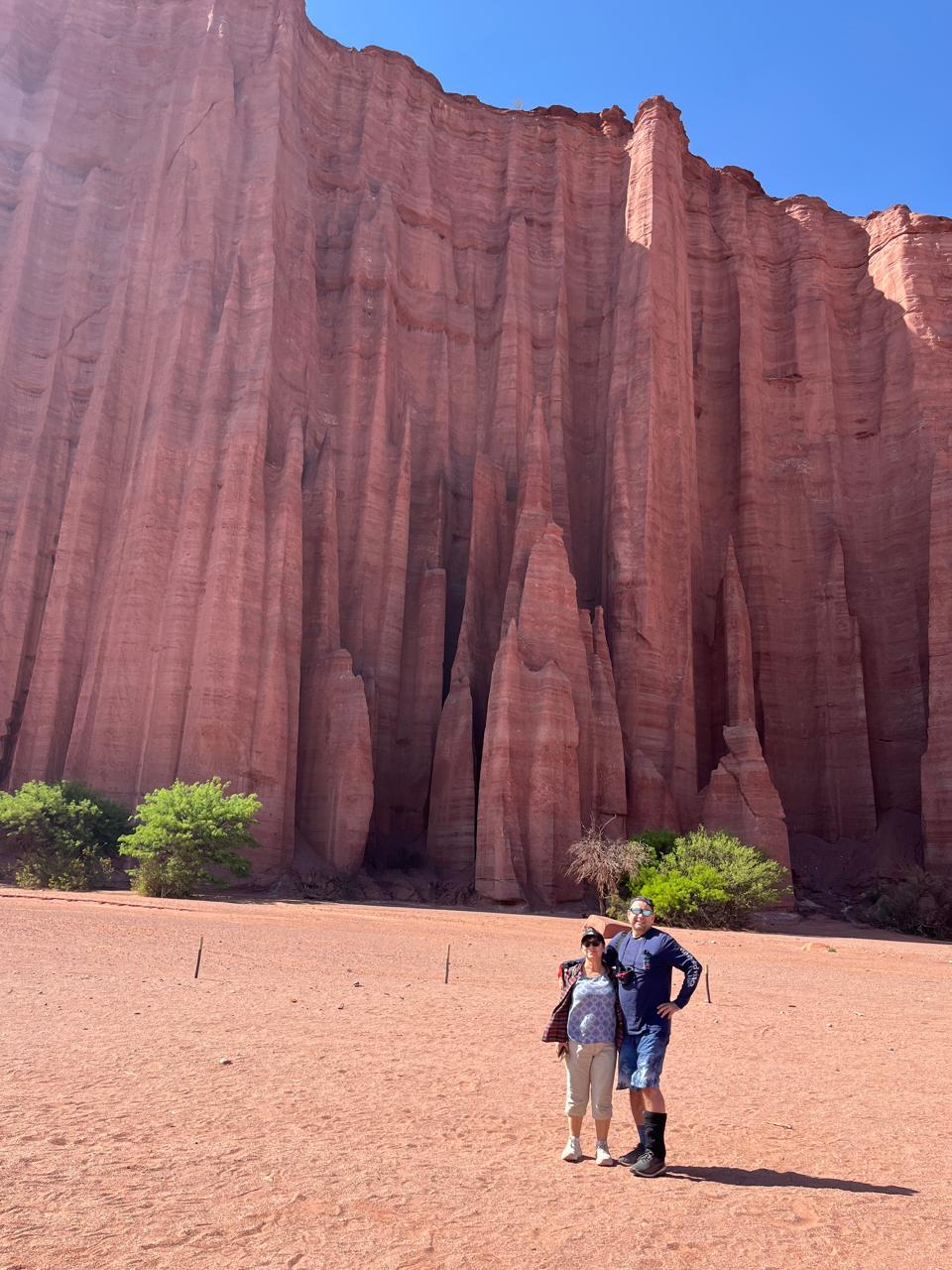 Mujer sentada sobre un tronco frente a una cascada doble en un bosque frondoso de Argentina.