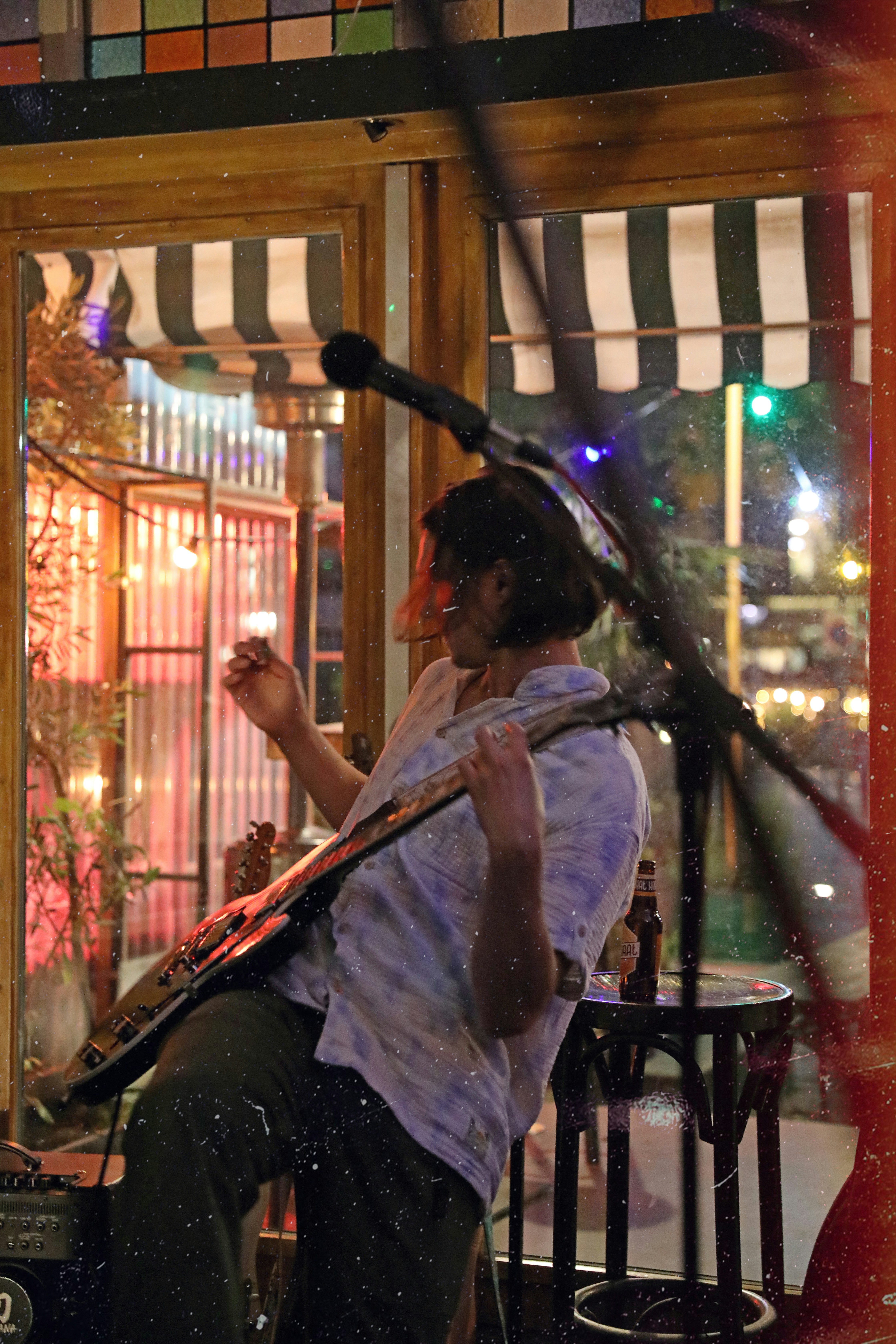 a man playing a guitar in front of a window