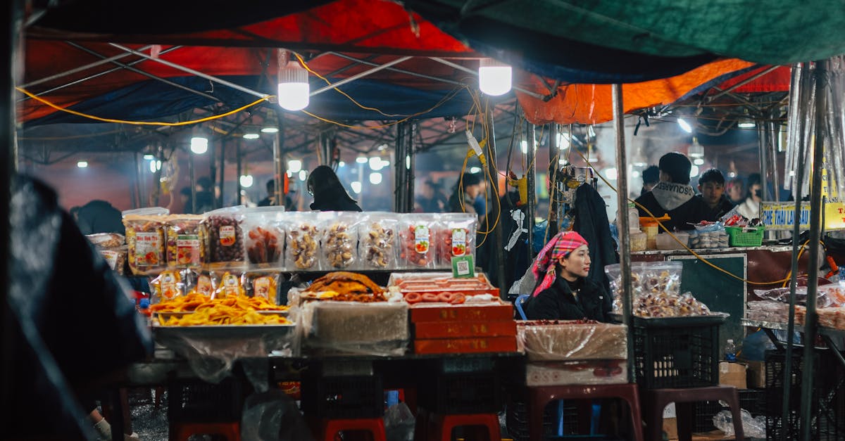A bustling night market scene featuring vendors with various food items, illuminated by colorful lig