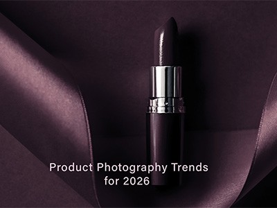 A sleek, dark lipstick is elegantly placed on a folded, rich purple satin fabric, showcasing modern product photography trends for 2026.