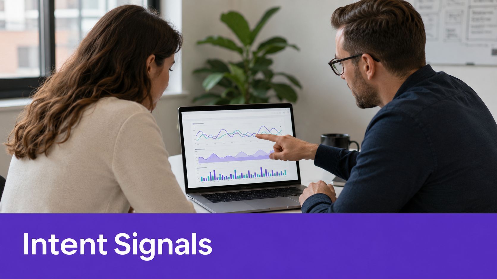 A professional man and woman analyzing data graphs on a laptop screen during a business meeting.