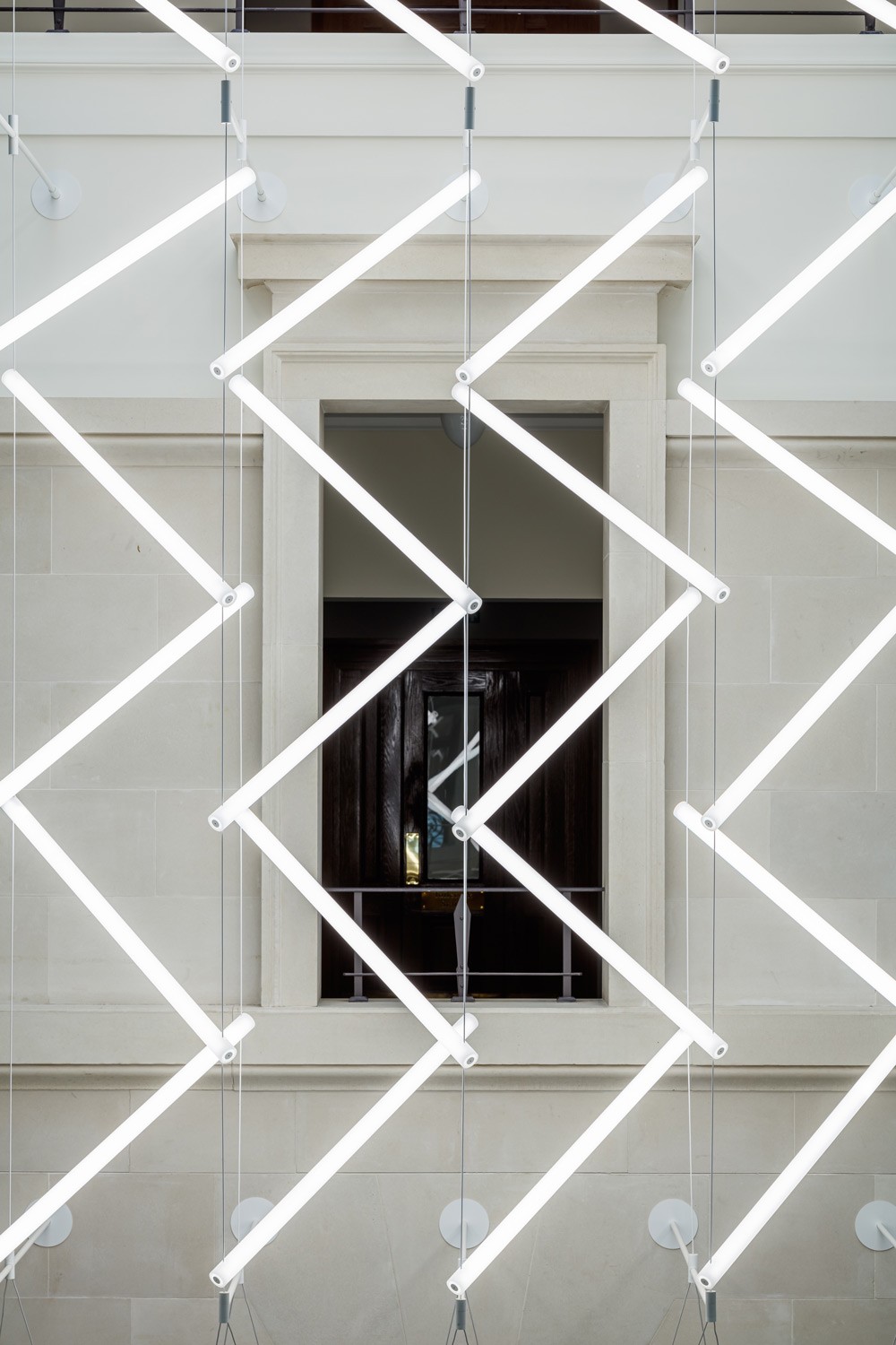 Close-up of custom acrylic LED light units suspended on tensioned steel cables