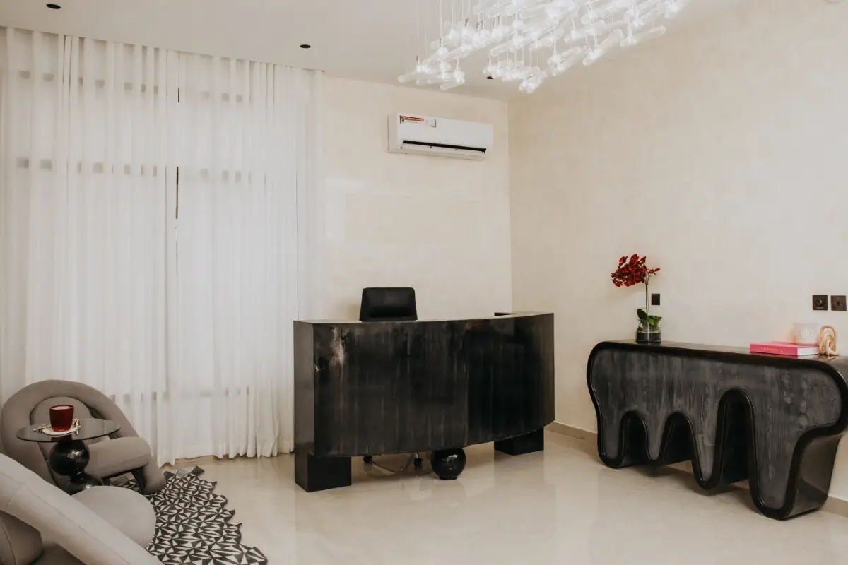 A modern kitchen and living room with white cabinets, herringbone floors, and a gray sectional sofa.