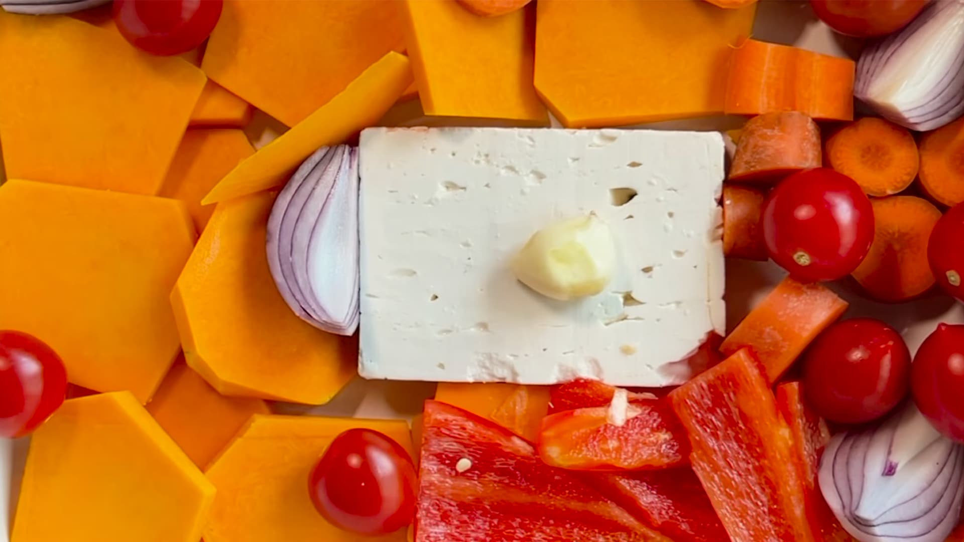 Frische Zutaten für Kürbis-Feta-Pasta, darunter Hokkaido-Kürbis, Feta, rote Zwiebeln, Cherrytomaten und Paprika – gesunde und proteinreiche Pasta-Zubereitung.