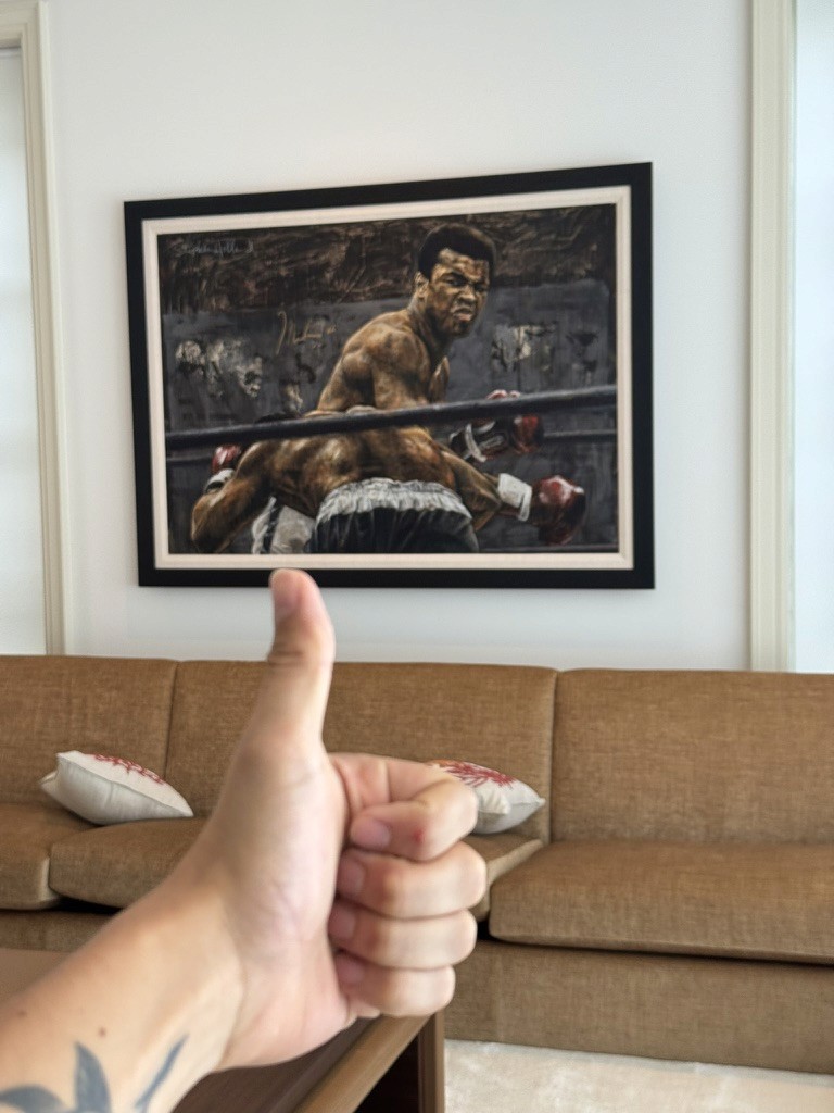 Framed painting of a boxer standing over a fallen opponent, displayed above a sofa